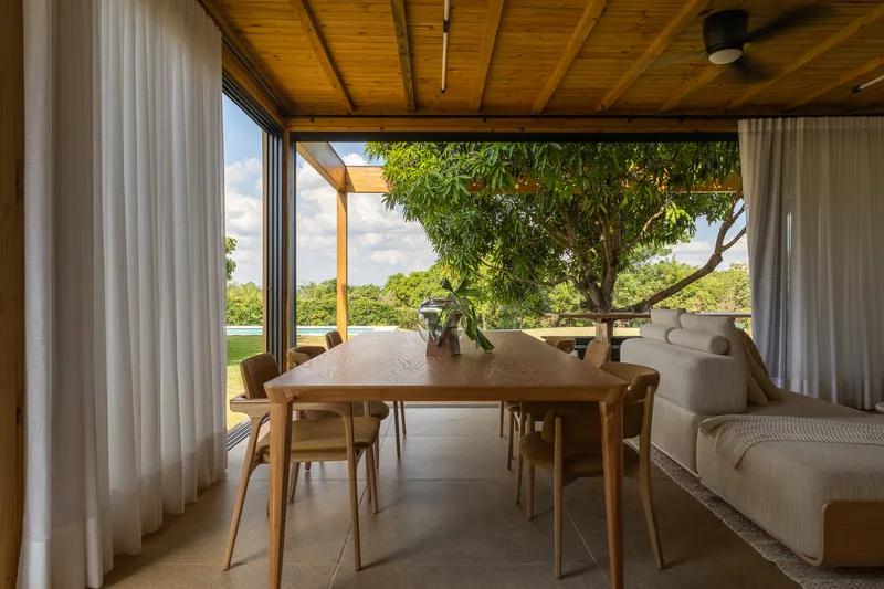 Dining table framed by corner glazing with views to landscape and tree canopy