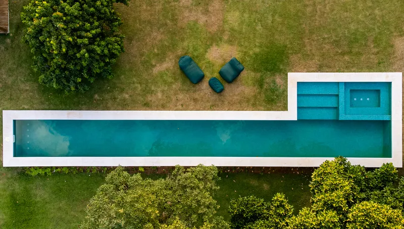 Aerial view of the linear pool with integrated spa and green lounge furniture on lawn