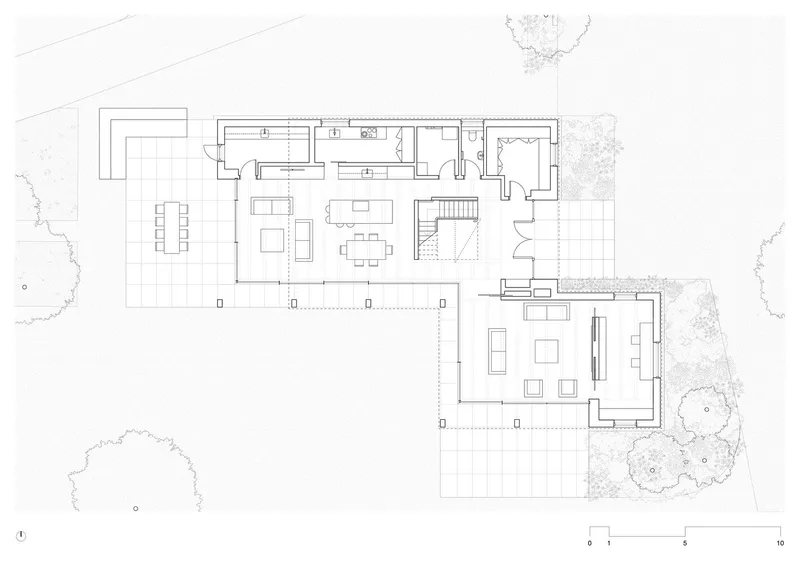 Floor plan drawing showing two connected volumes with living spaces and a central staircase surrounded by landscaping