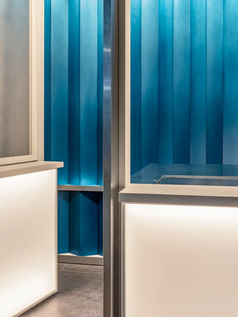 Interior view showing blue vertical fabric panels and white counter with slim metal framing