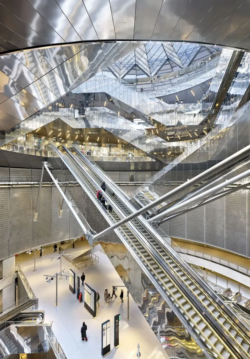 Atrium view with crisscrossing escalators and a faceted mirrored ceiling reflecting multiple levels below