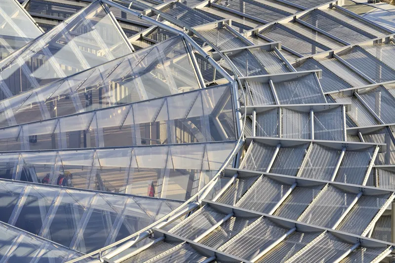 Close-up of the glazed roof structure with angled glass panels and steel framing in daylight