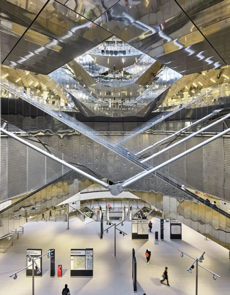 Multi-story atrium with mirrored ceiling panels and crisscrossing escalators above a lobby with scattered visitors