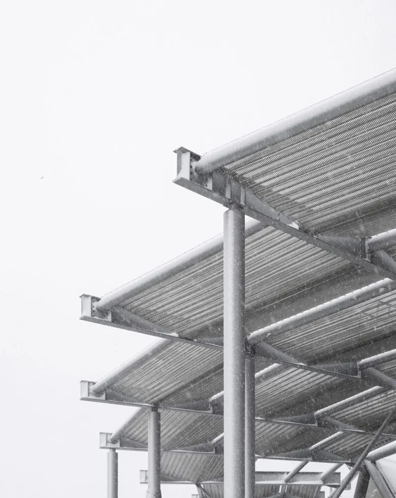 Underside view of cantilevered perforated metal canopy panels supported by tubular steel columns