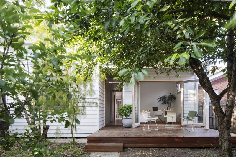 Timber deck extension opening to interior living space through established garden trees