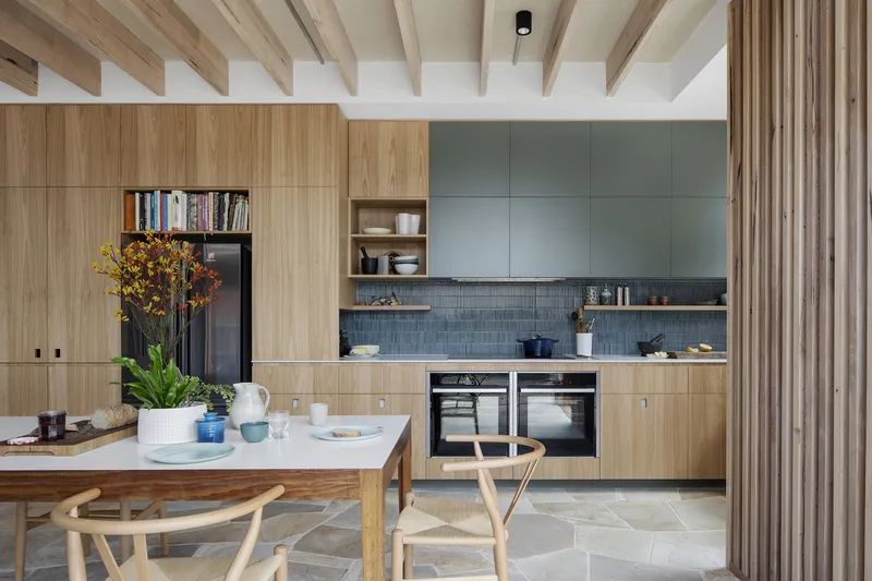 Kitchen with timber cabinetry, blue tiled splashback and exposed timber ceiling joists