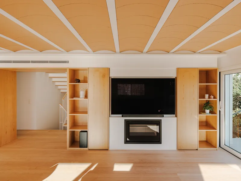 Living room with white built-in cabinetry flanking a fireplace beneath plywood ceiling with exposed white beams