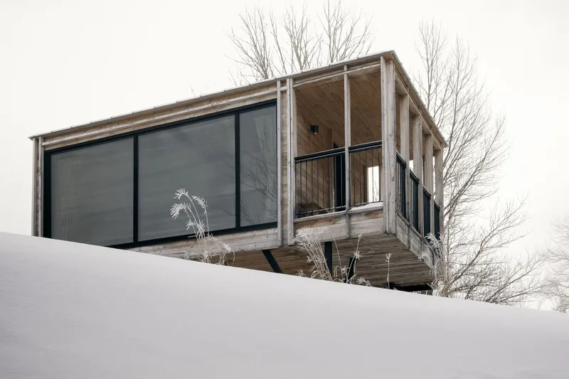Cantilevered deck with timber posts and metal railing on a slope overlooking bare winter trees