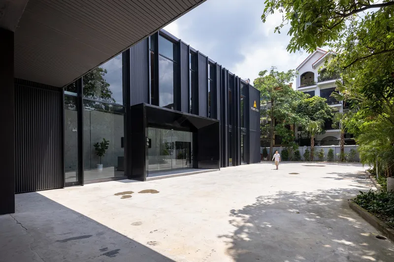 Concrete courtyard with planted borders and corrugated metal canopy casting dappled shadows