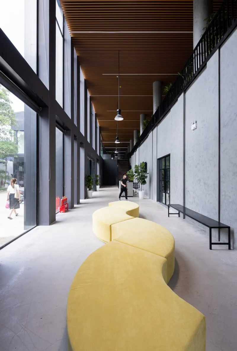 Interior corridor with timber slatted ceiling and yellow serpentine seating along concrete floor