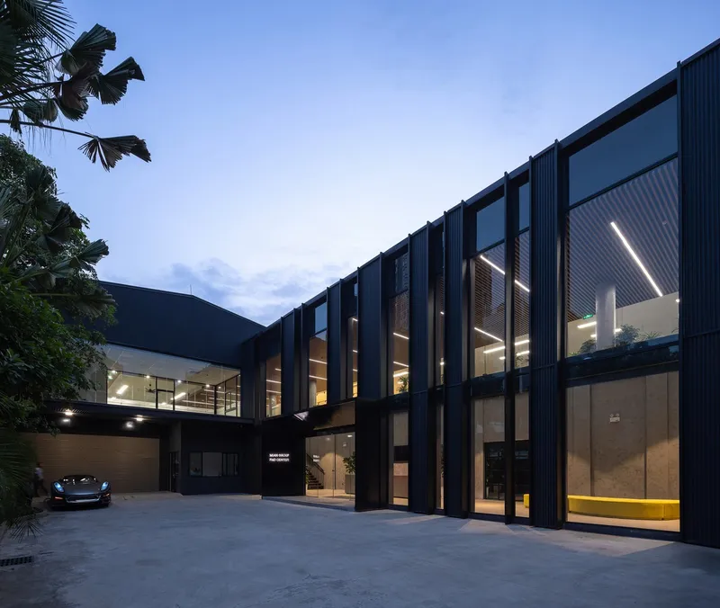 Courtyard facade with vertical metal fins and illuminated interior spaces at twilight