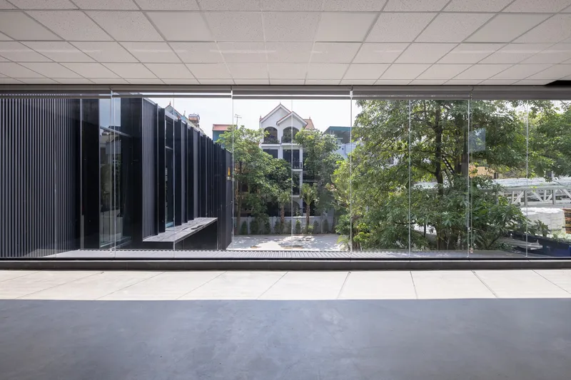 Interior corridor with drop ceiling tiles looking out through full-height glass to a courtyard with trees