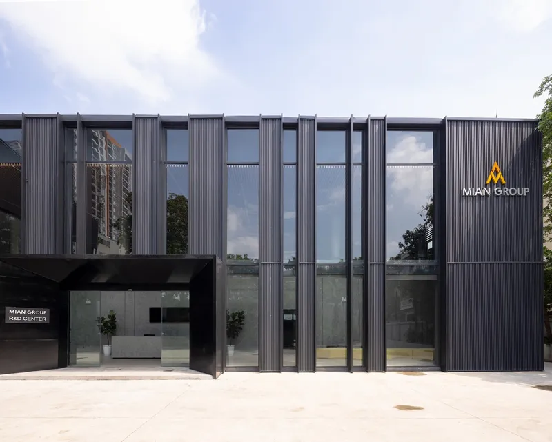 Entrance facade with alternating vertical metal fins and glazed bays under midday sun