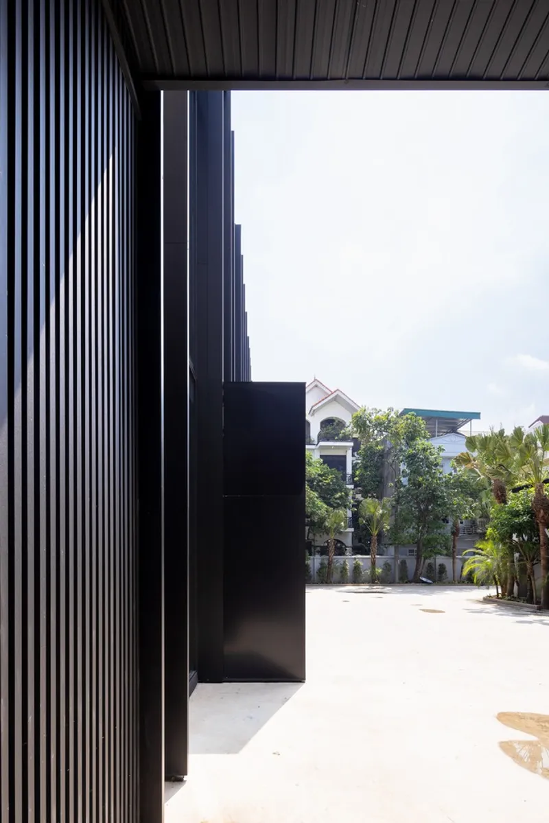 Corner detail showing ribbed metal cladding and black volumetric projection facing a residential street