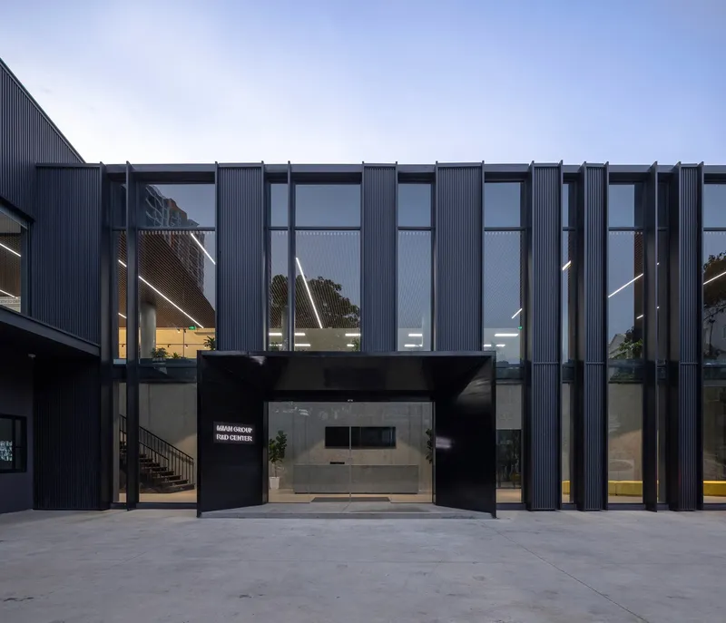 Front elevation with cantilevered upper floor supported by glass-enclosed reception area at twilight