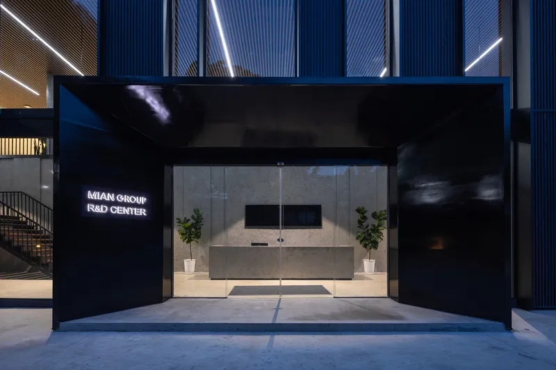 Reception desk with stone counter and flanking potted plants beneath a black canopy at dusk