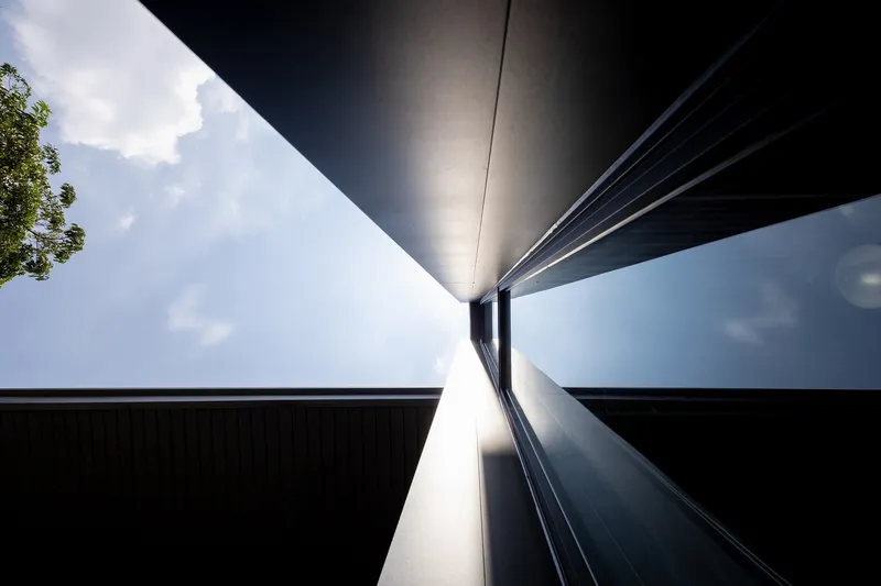Worm's-eye view of converging metal-clad volumes meeting at a central glazed junction