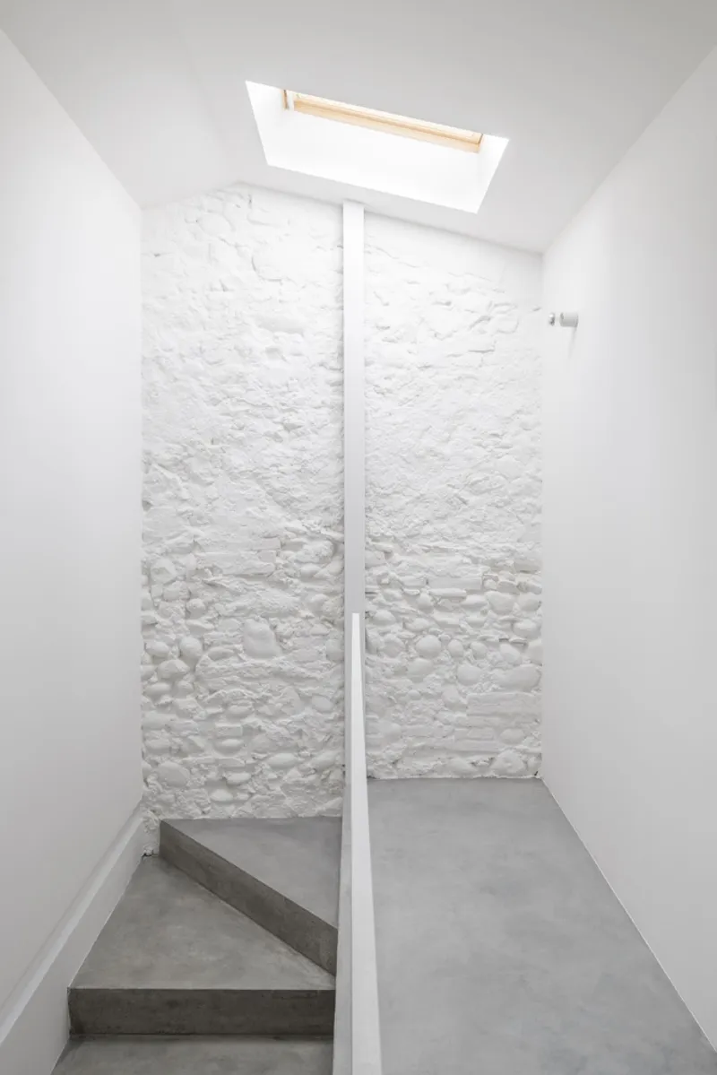Shower enclosure with white painted brick wall and skylight with timber frame above