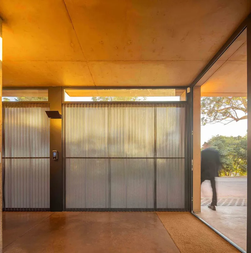 Interior room with translucent corrugated wall panels and plywood ceiling lit by afternoon sun