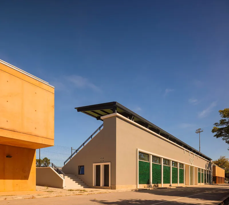 External staircase leading to a cantilevered roof above a row of green shuttered openings