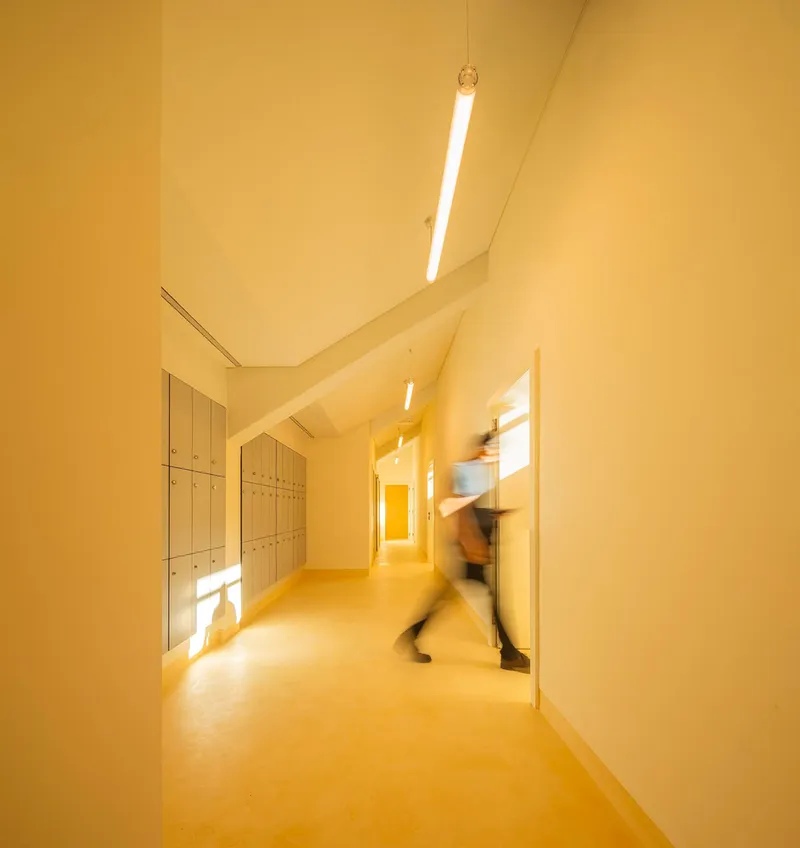 Corridor with yellow resin flooring and wall-mounted lockers as a figure passes in motion blur