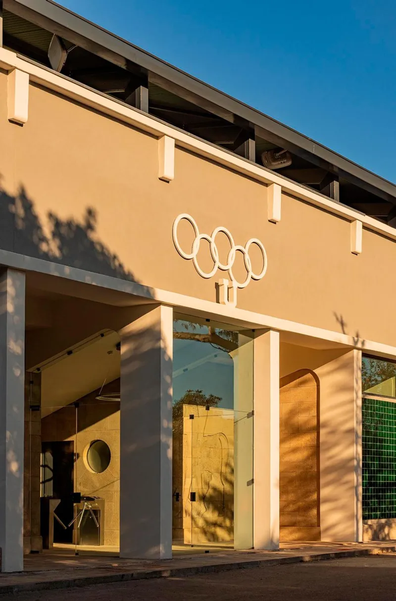 Entrance portico with white cylindrical columns and Olympic rings graphic under warm afternoon light