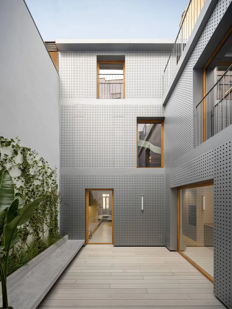 Courtyard with perforated metal panels, timber decking, and a planted bed with climbing vines