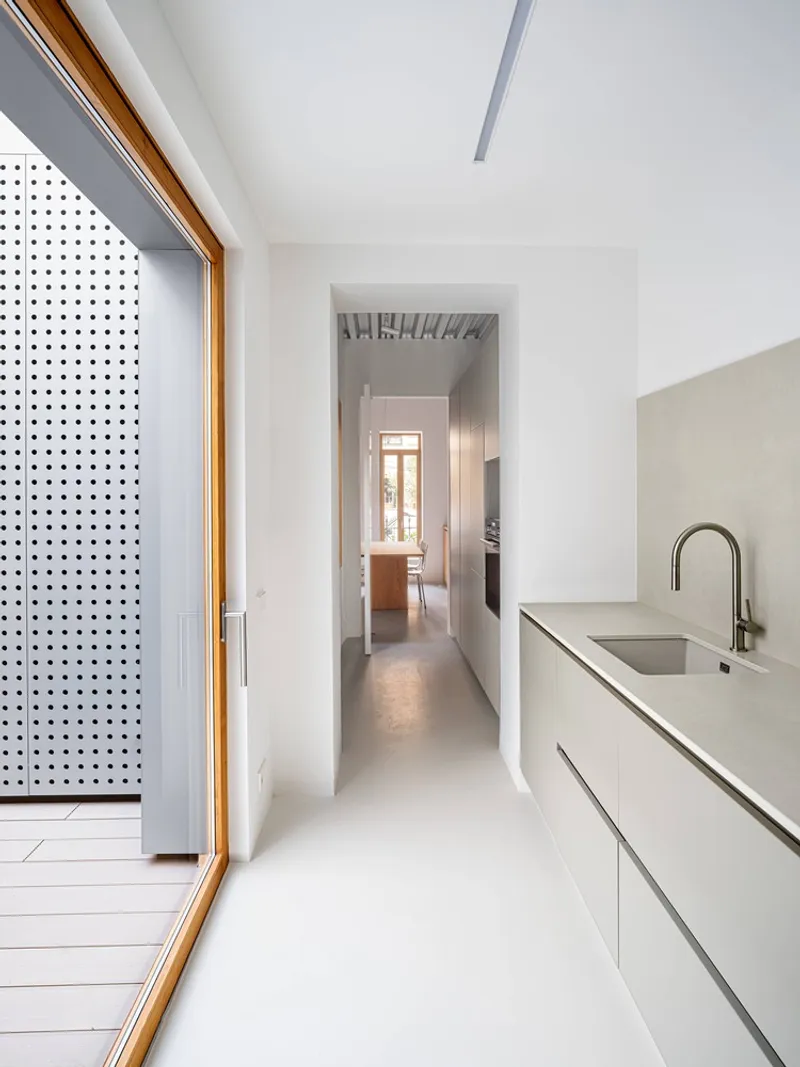 White kitchen corridor with sliding door to deck and view through to rear rooms
