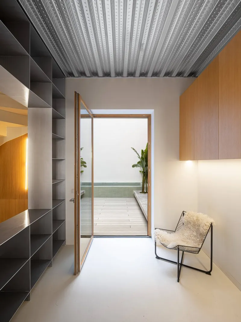 Hallway with corrugated metal ceiling, built-in shelving, and timber-framed door to exterior terrace