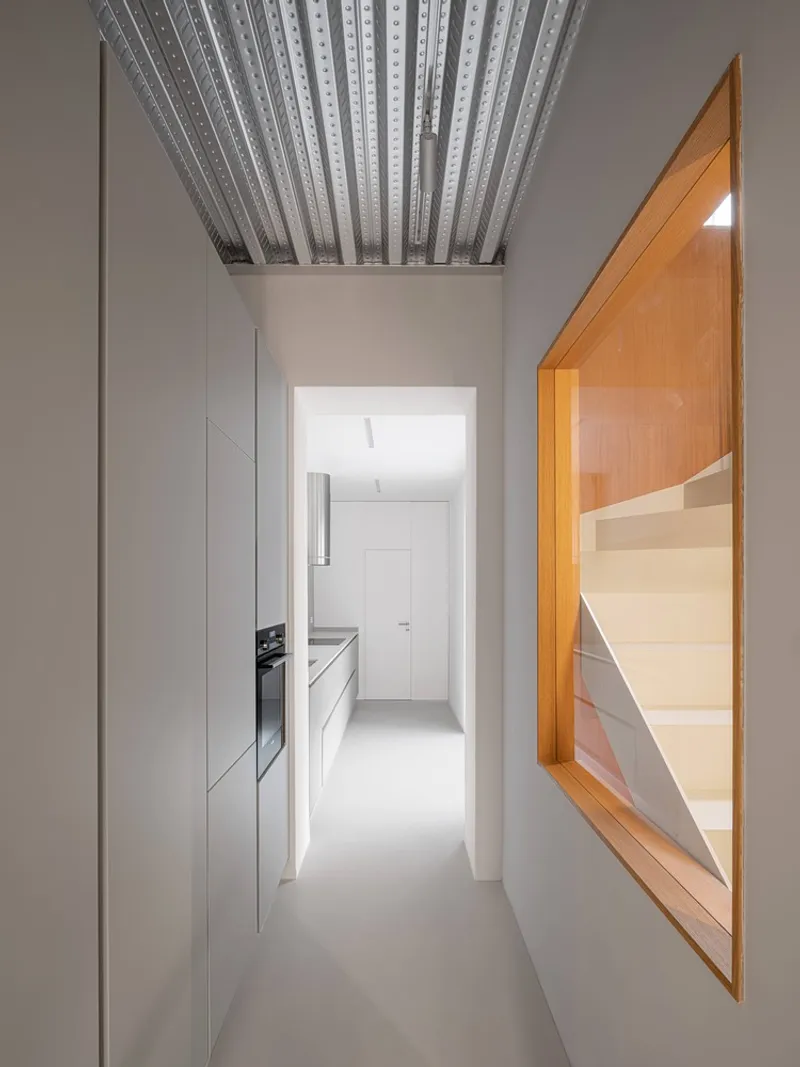 Corridor with white cabinetry on the left and a timber-framed opening revealing the staircase beyond