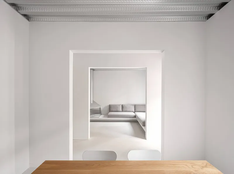 Aligned doorways framing a view through to a grey sectional sofa under perforated metal ceilings