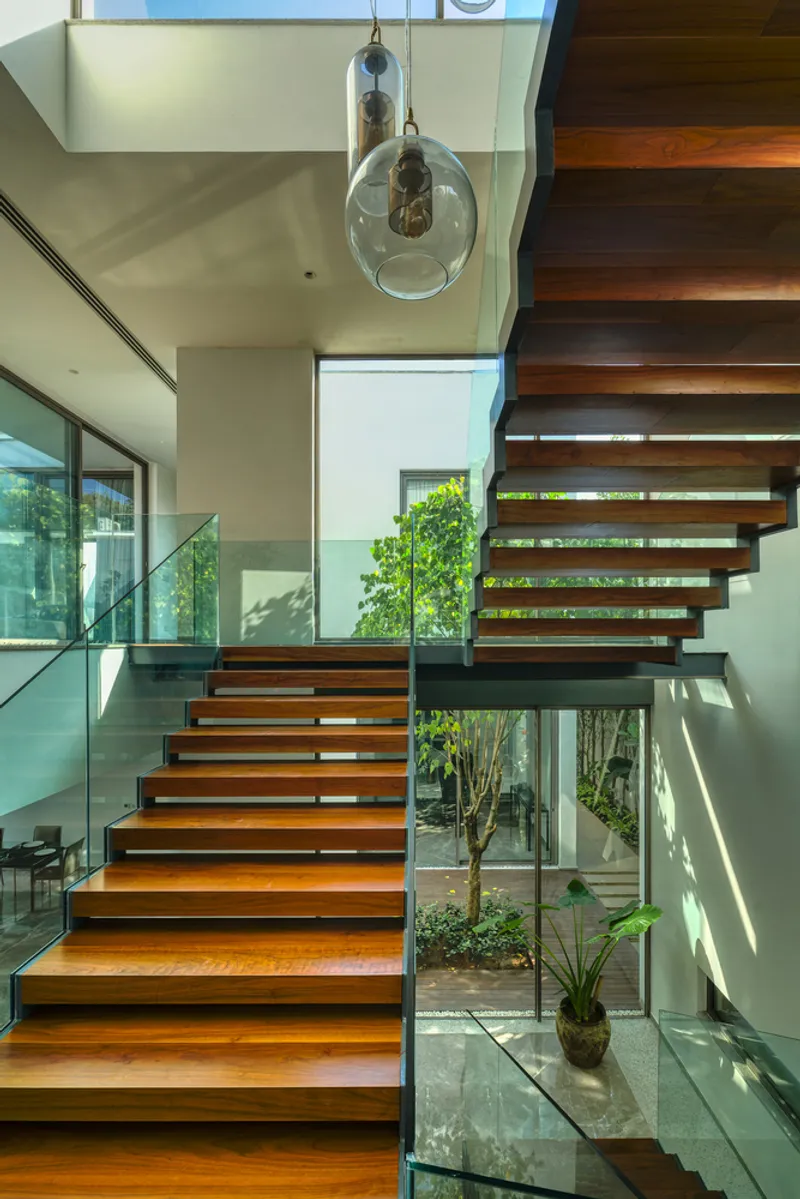 Floating timber staircase with glass balustrade and pendant lights in double-height space
