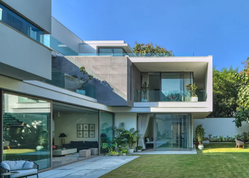 Garden elevation showing stacked concrete volumes with floor-to-ceiling glazing overlooking the lawn