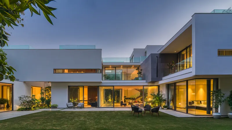 Rear elevation at dusk with illuminated interiors and terraced volumes facing the garden