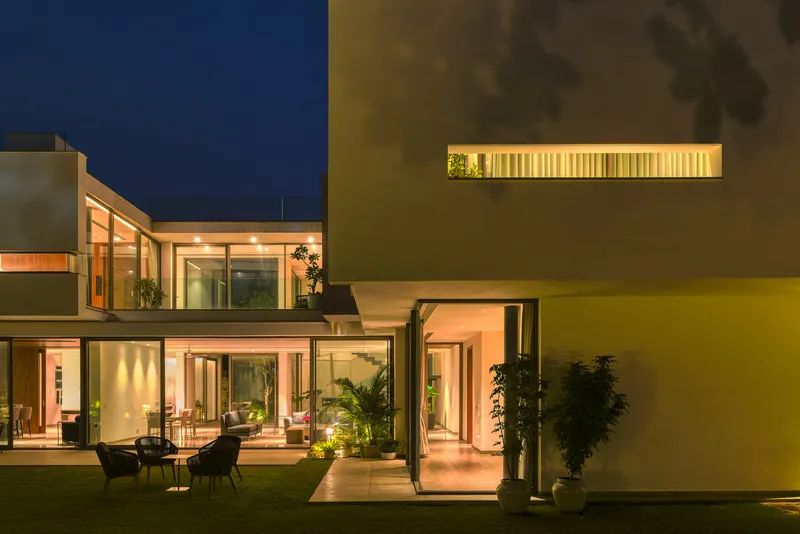 Night view of the courtyard with backlit horizontal window slot and yellow painted wall plane