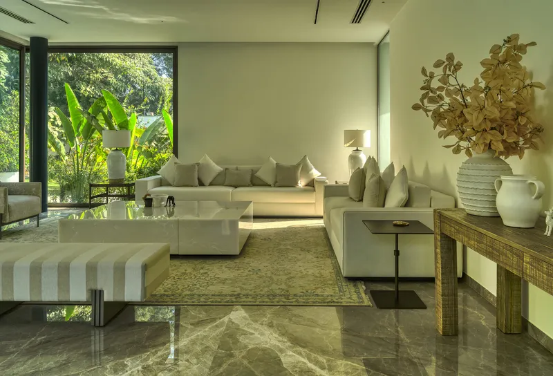 Living room with polished stone floor and full-height glazing overlooking garden