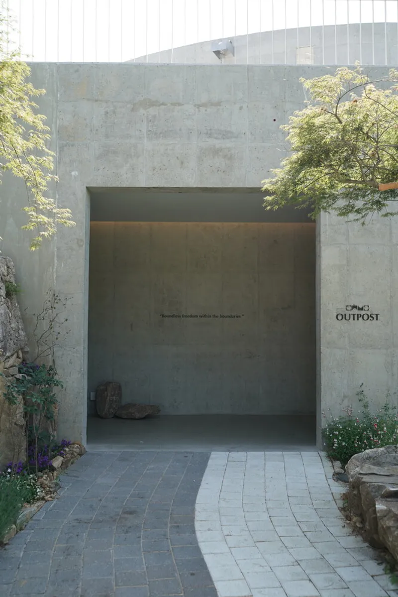 Entrance portal through board-formed concrete walls flanked by planted beds and pavers