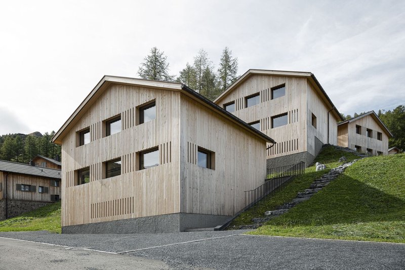 Two staggered gable volumes clad in vertical timber with slatted screening beneath cloudy skies