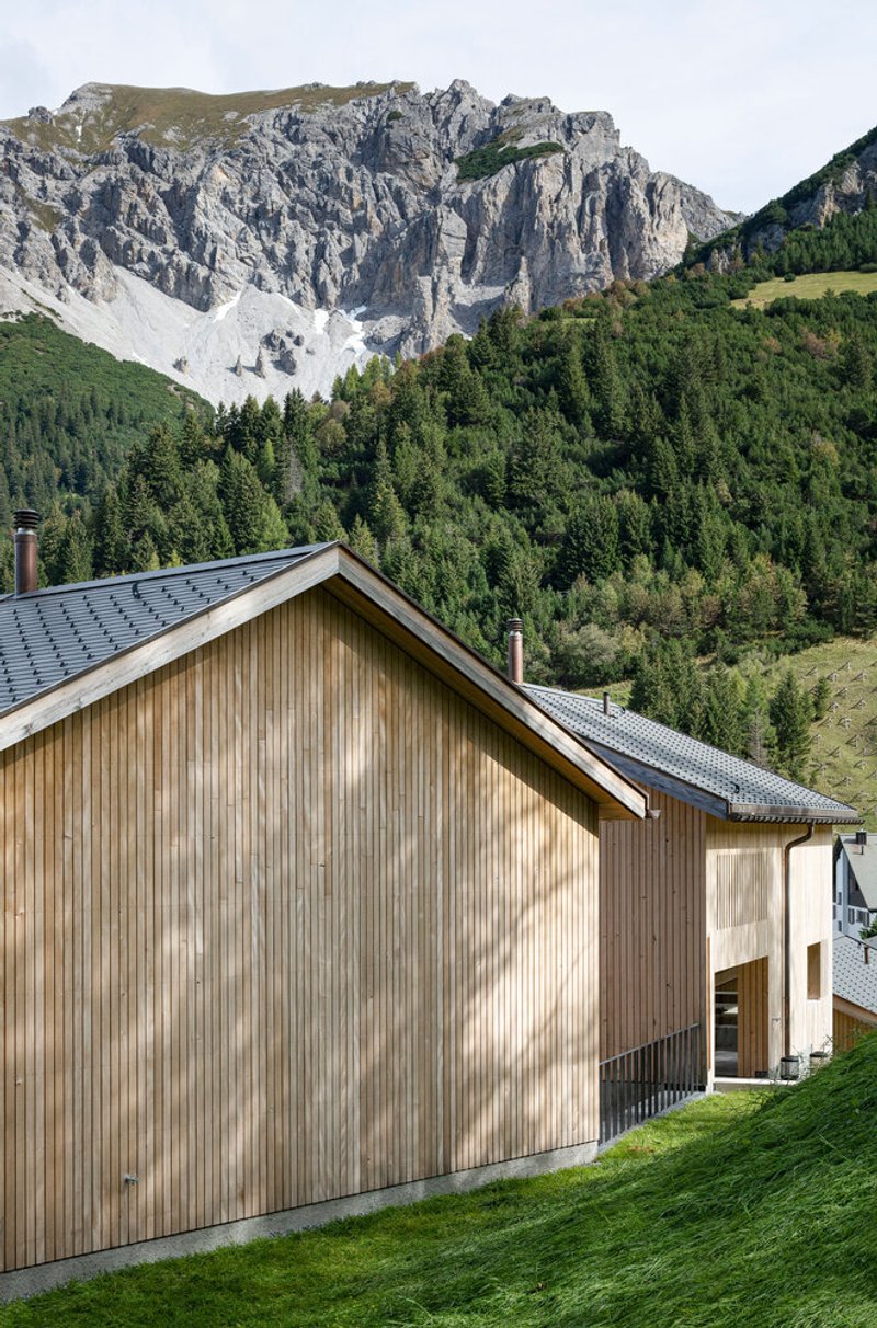 Timber gable end with vertical cladding set against forested slopes and exposed limestone cliffs