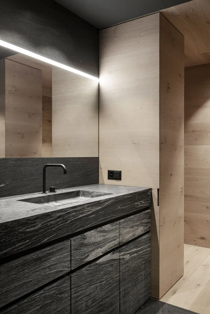 Bathroom vanity with integrated stone basin and linear light above pale timber wall panels
