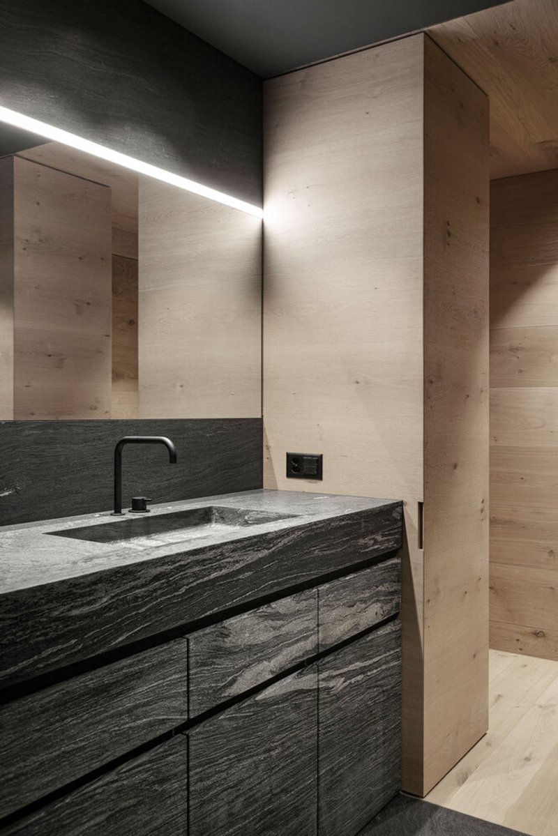 Bathroom vanity with integrated stone basin and linear light above pale timber wall panels