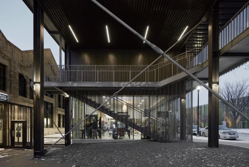 Covered entrance canopy with diagonal steel bracing and vertical metal cladding at twilight