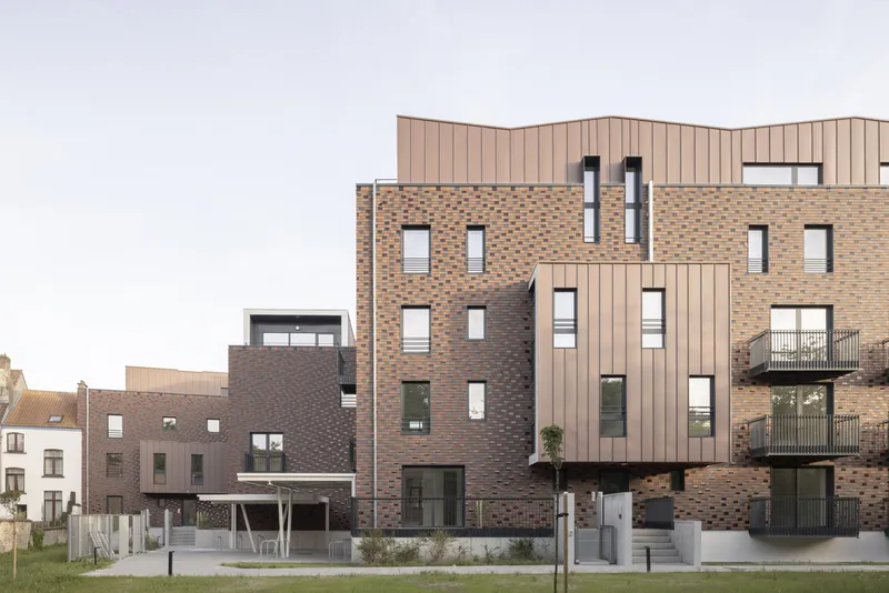Rear facade of mixed brick and vertical timber cladding volumes overlooking a grass lawn