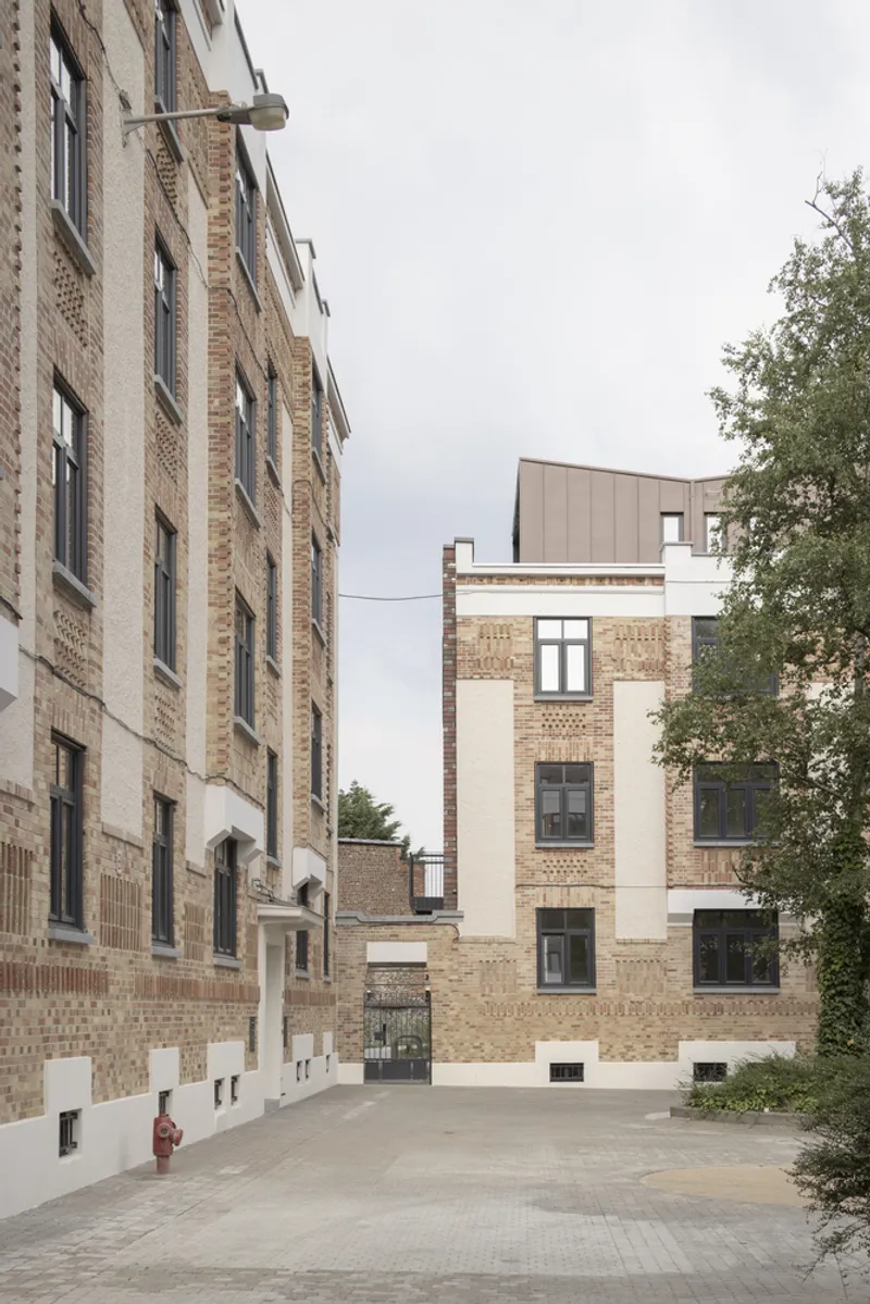 Shared courtyard view between brick facades with paved ground and a single tree