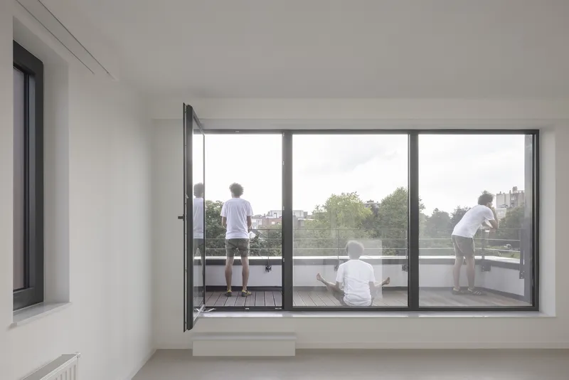 Interior living room with floor-to-ceiling glazed doors opening to a timber-decked terrace with children playing