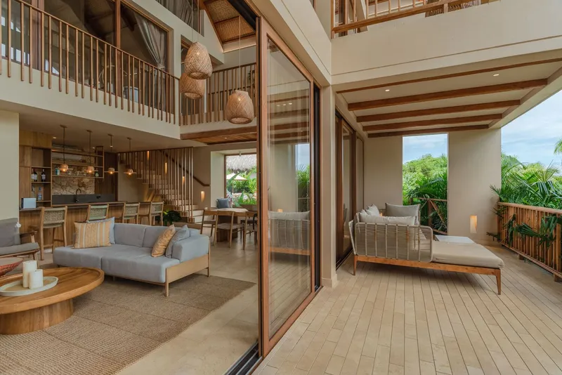 Double-height interior with timber screen and sliding glass partition opening to shaded terrace