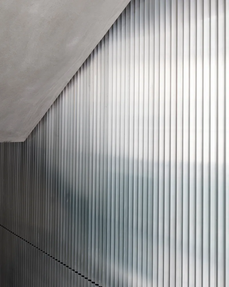 White vertical ribbed wall panels meeting at an angular ceiling edge in diffused light