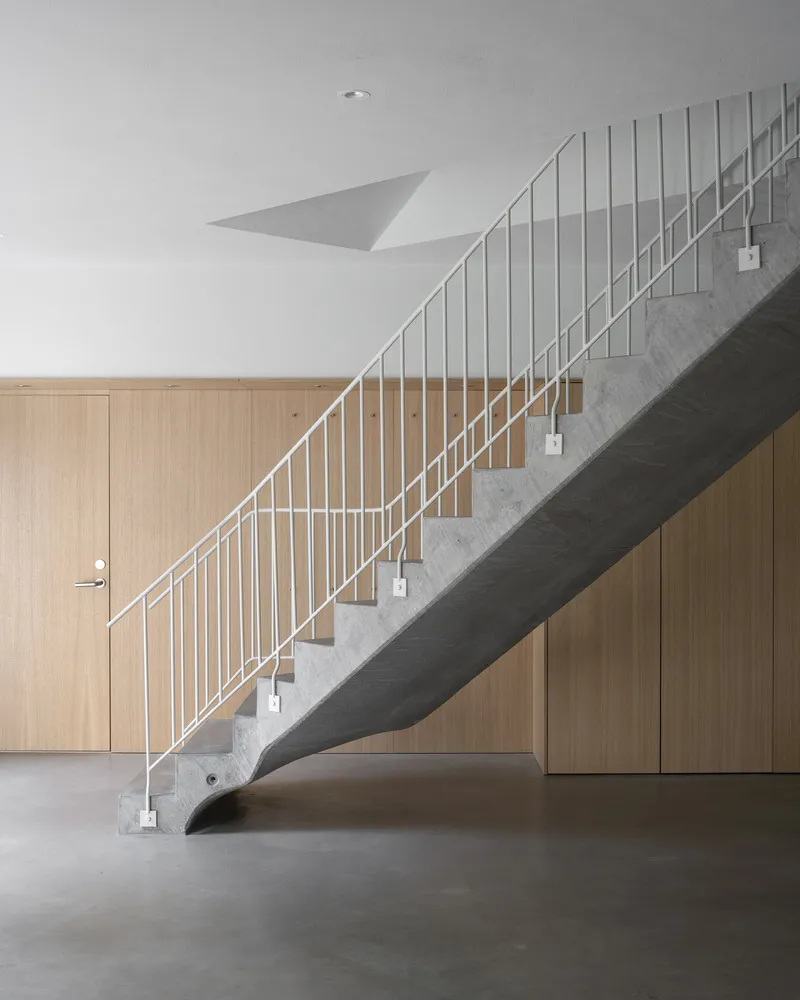 Concrete staircase with white vertical rod balustrade against timber-clad storage wall