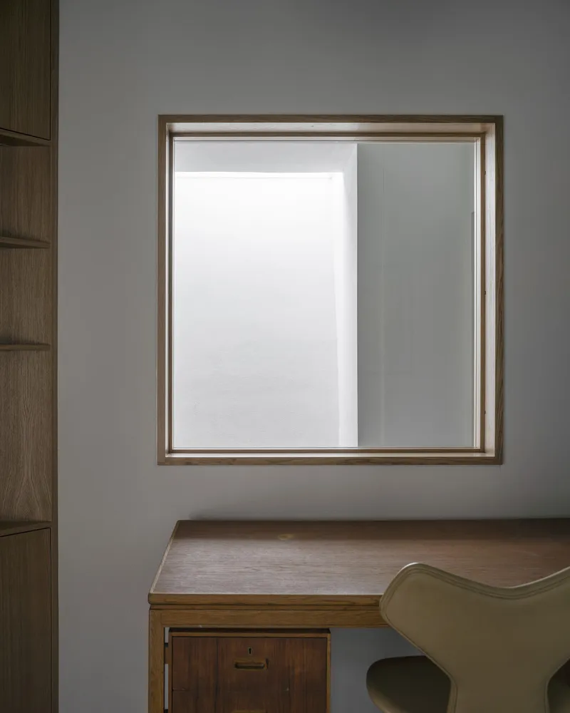Timber-framed window above a wooden desk and chair in soft diffused daylight