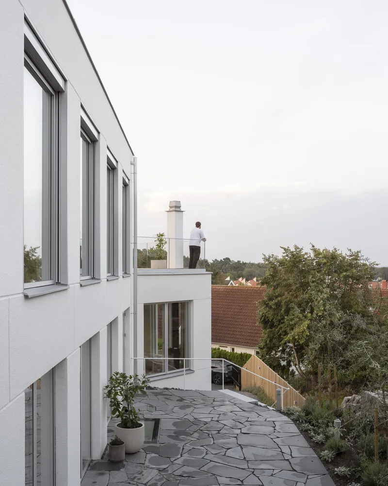 Roof terrace with flagstone paving and a figure standing at the parapet at dusk